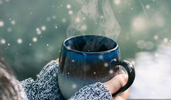 Woman with long brown hair drinking hot tea on snowy day in moun